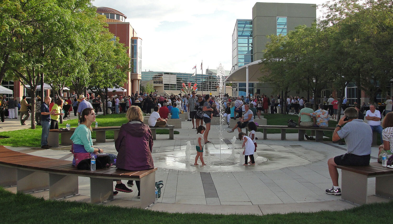 Kids play in a waterplay feature with seating around the perimeter.