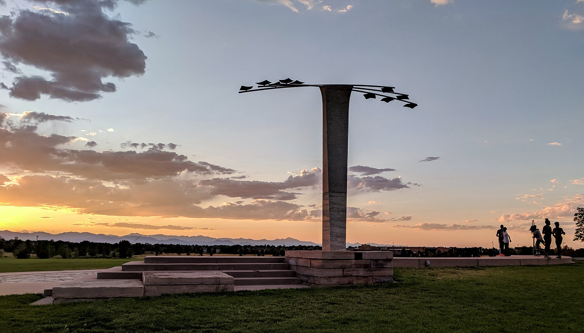 A photo of a monument shaped like a 'T' with the Rocky Mountains in the background.