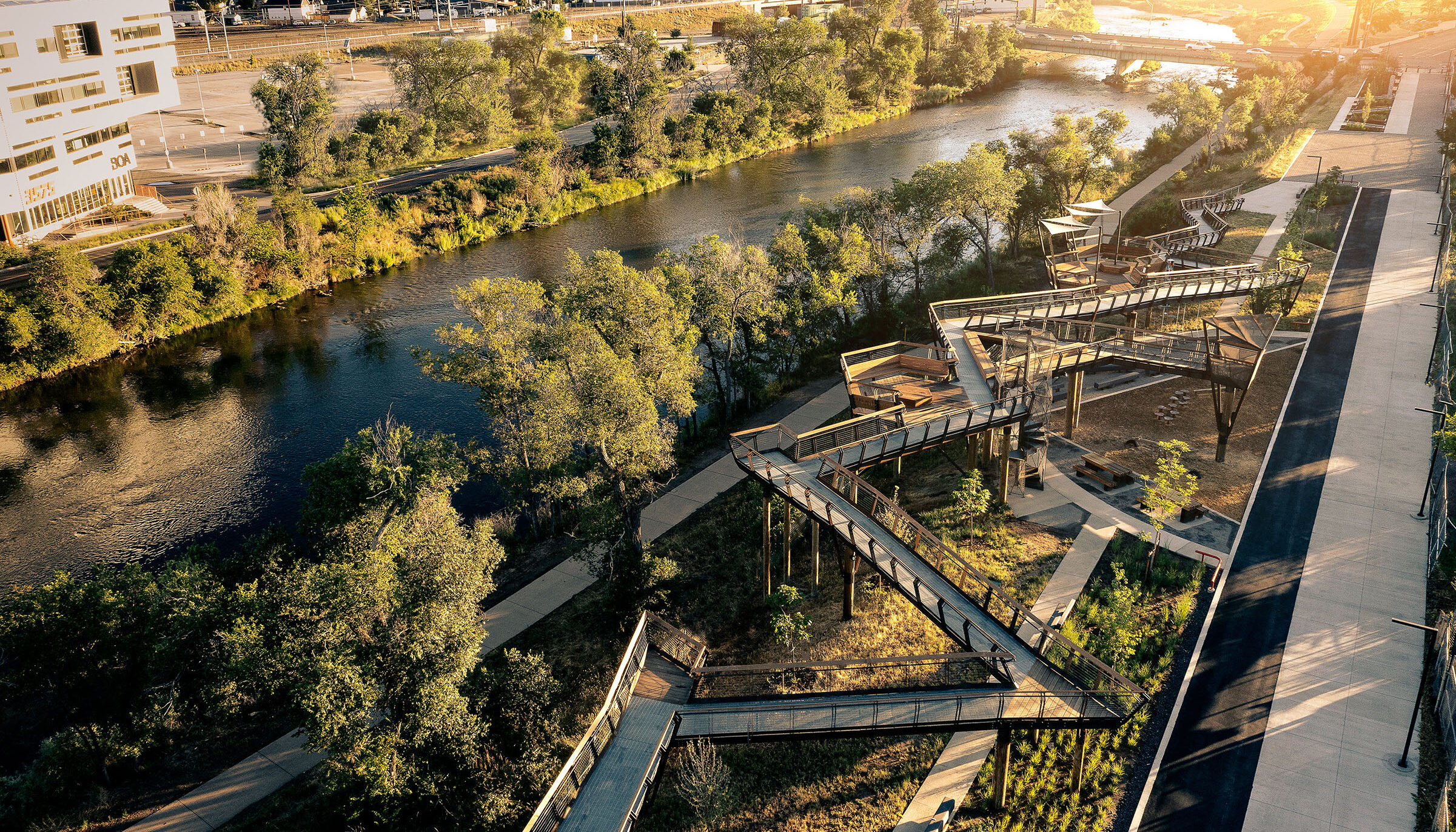 Early morning sunlight casts yellow light on the grand elevated walkway that zigzags through Arkins Promenade and provides views of the adjacent South Platte River below.