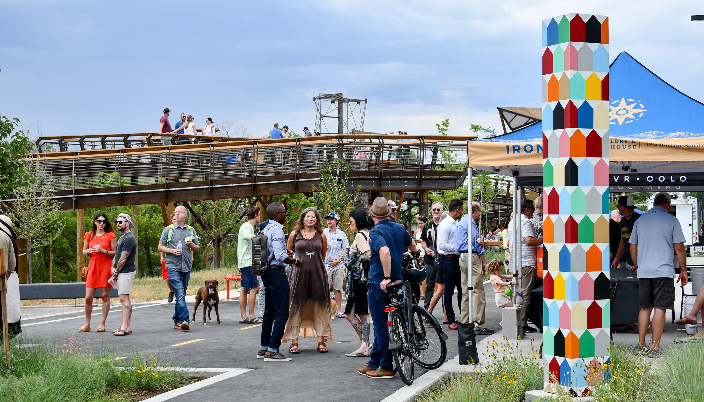 People enjoy themselves along Arkins Promenade and up on the elevated walkway which provides a lively, unique space for community gathering with art sculptures, and places food trucks and tents along the river.