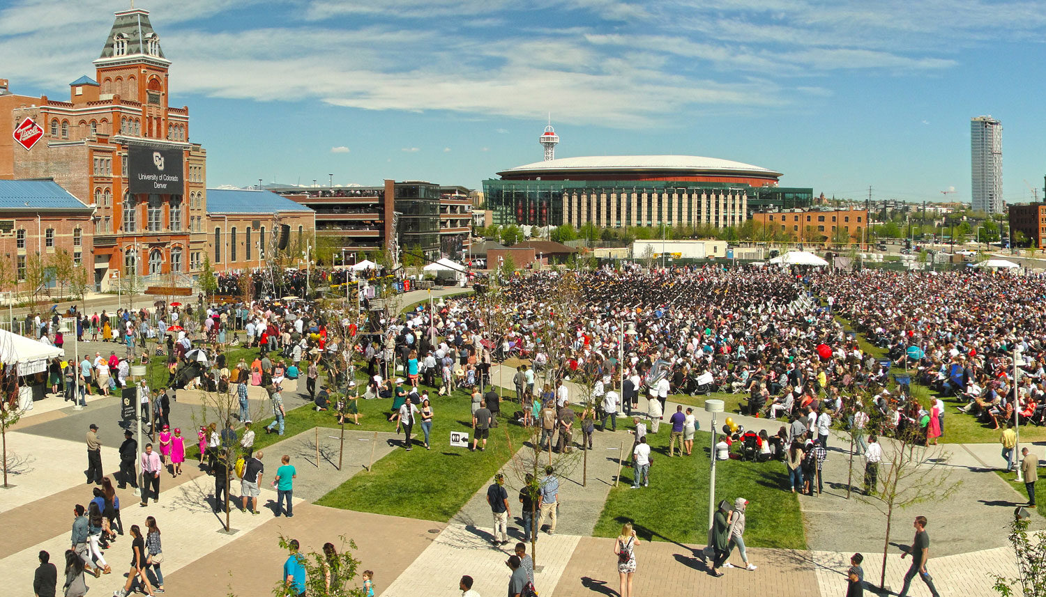 The quad is full of people seated for graduation sitting in rows.