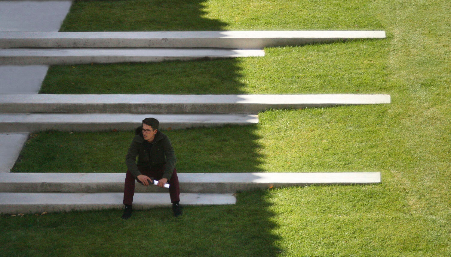 A student sits on concrete steps that extend into the hillside.