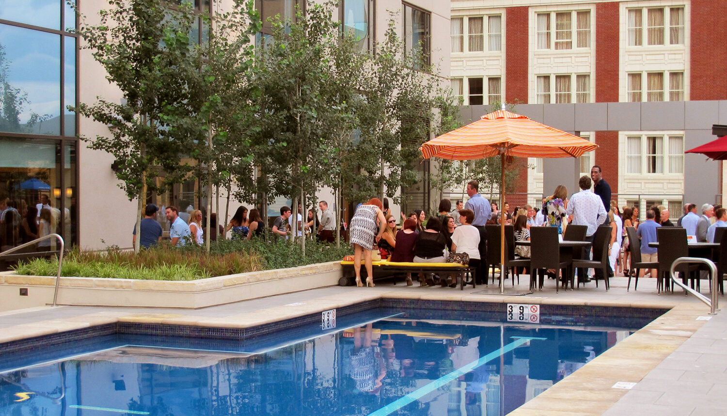 A photo of the pool with people gathered in the seating area adjacent to a small grove of aspen trees.