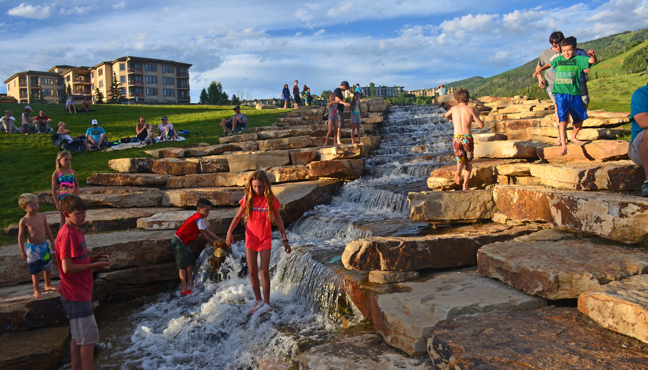 kids enjoy playing in the stone, slot-canyon waterfall-inspired water feature tucked into the mountain slope