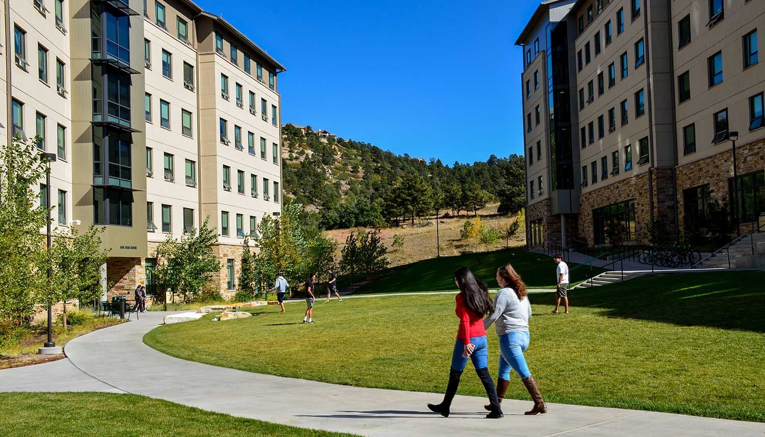 Student mill and play on a turf grass area between dorm buildings.