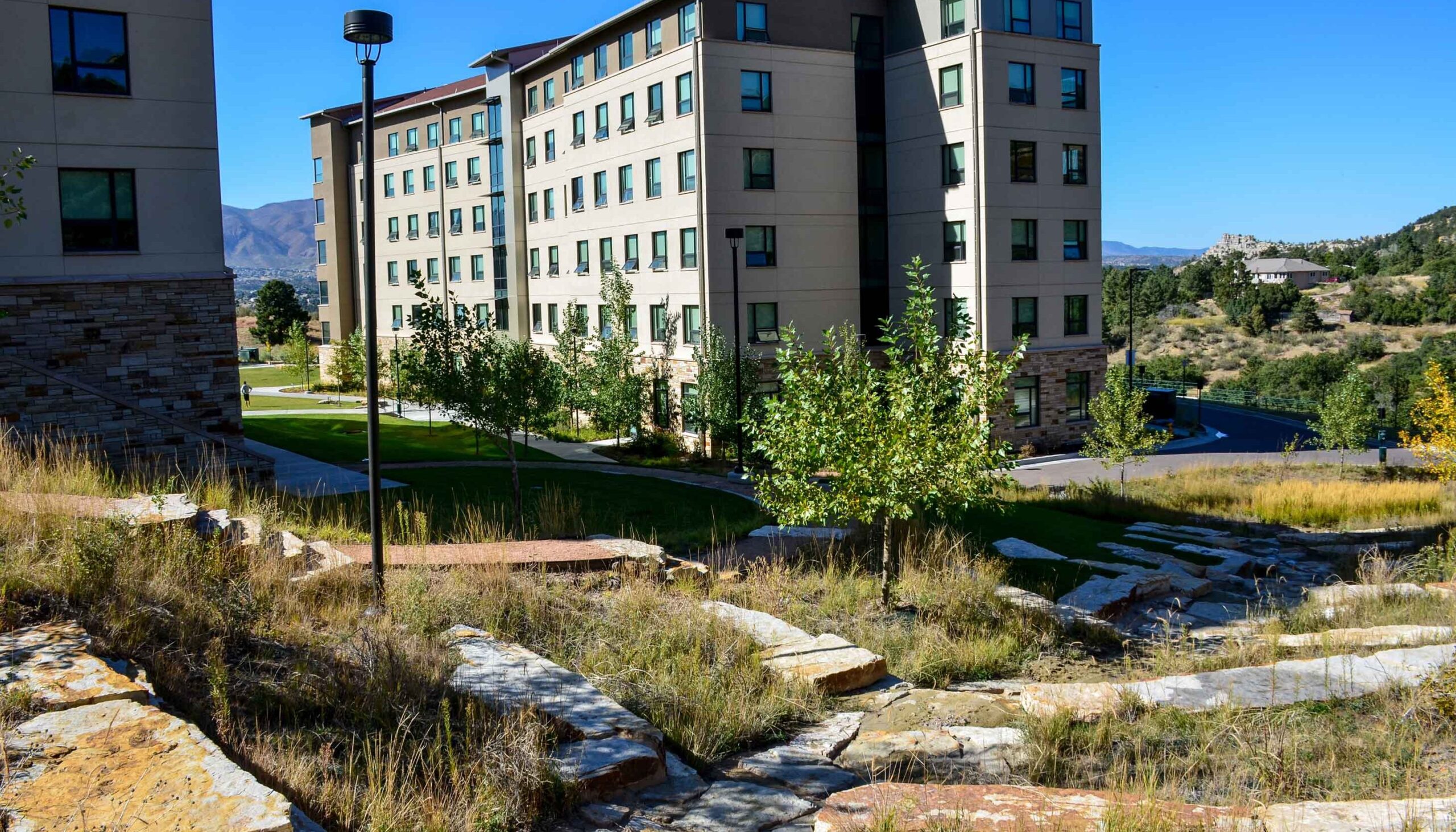 Stone berms for controlled stormwater, descend a hillside near the dorm buildings.