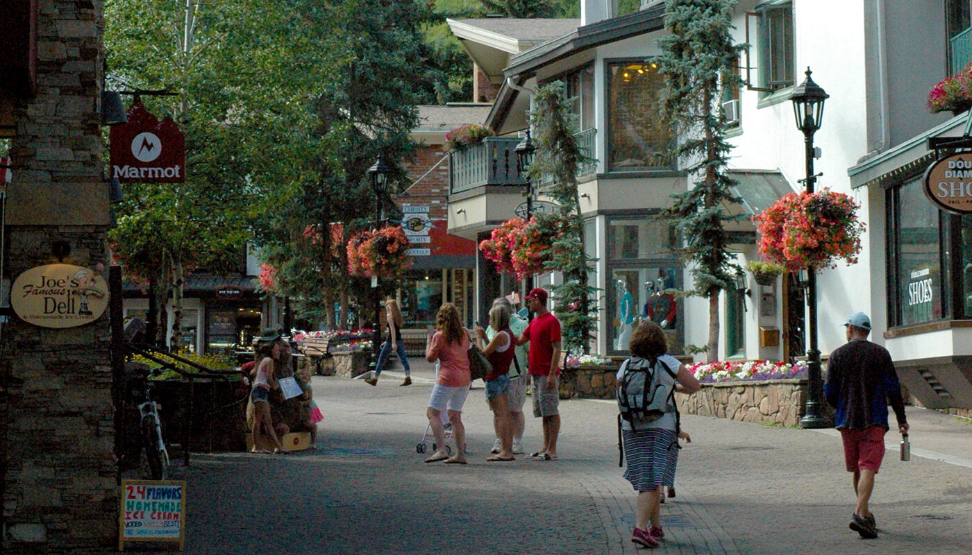 pedestrian streetscape with a view of the chairlift in the distance, large flowered pots hang along the street lights
