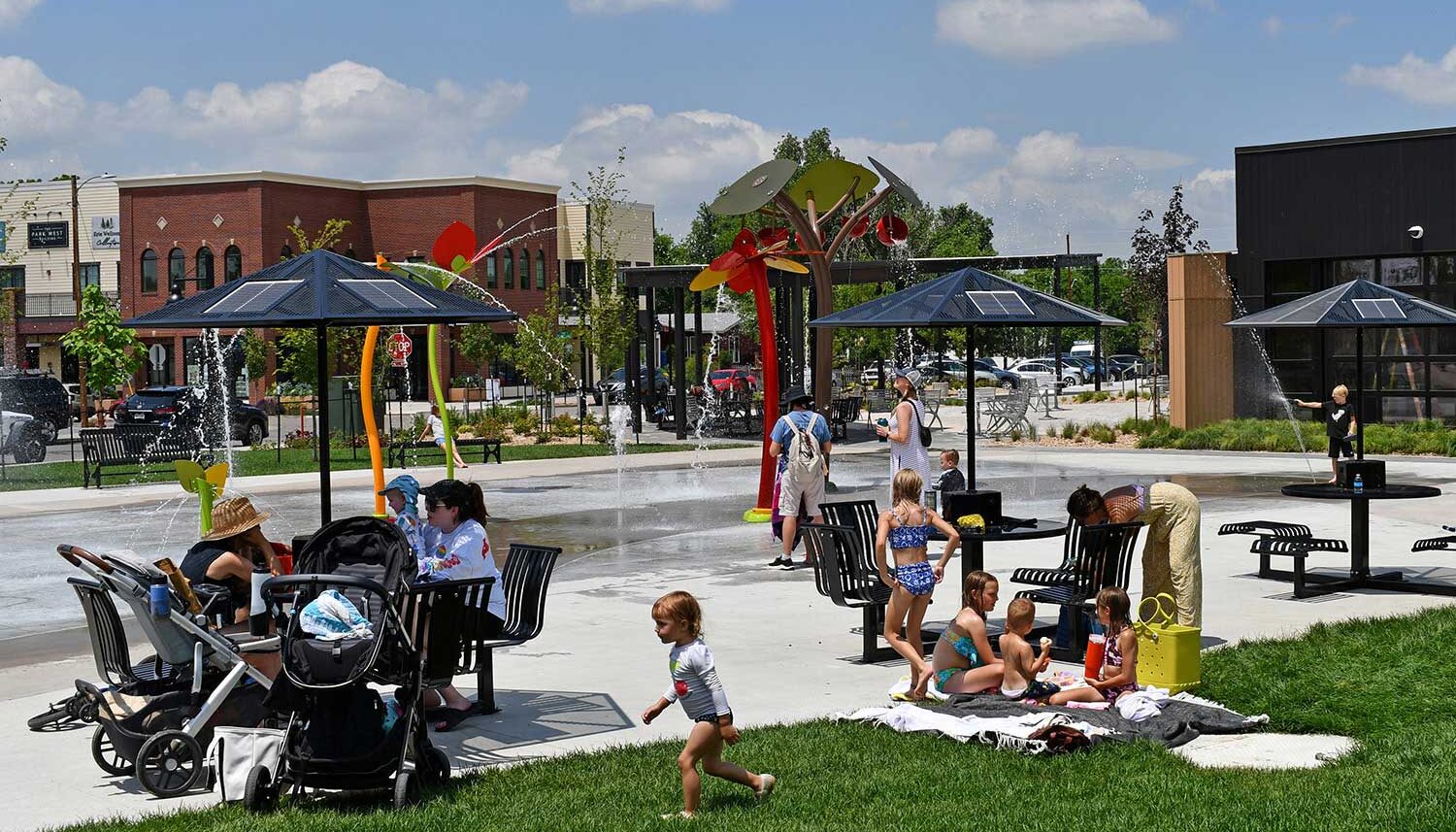 Families sit on shaded picnic tables as the water park runs behind them.