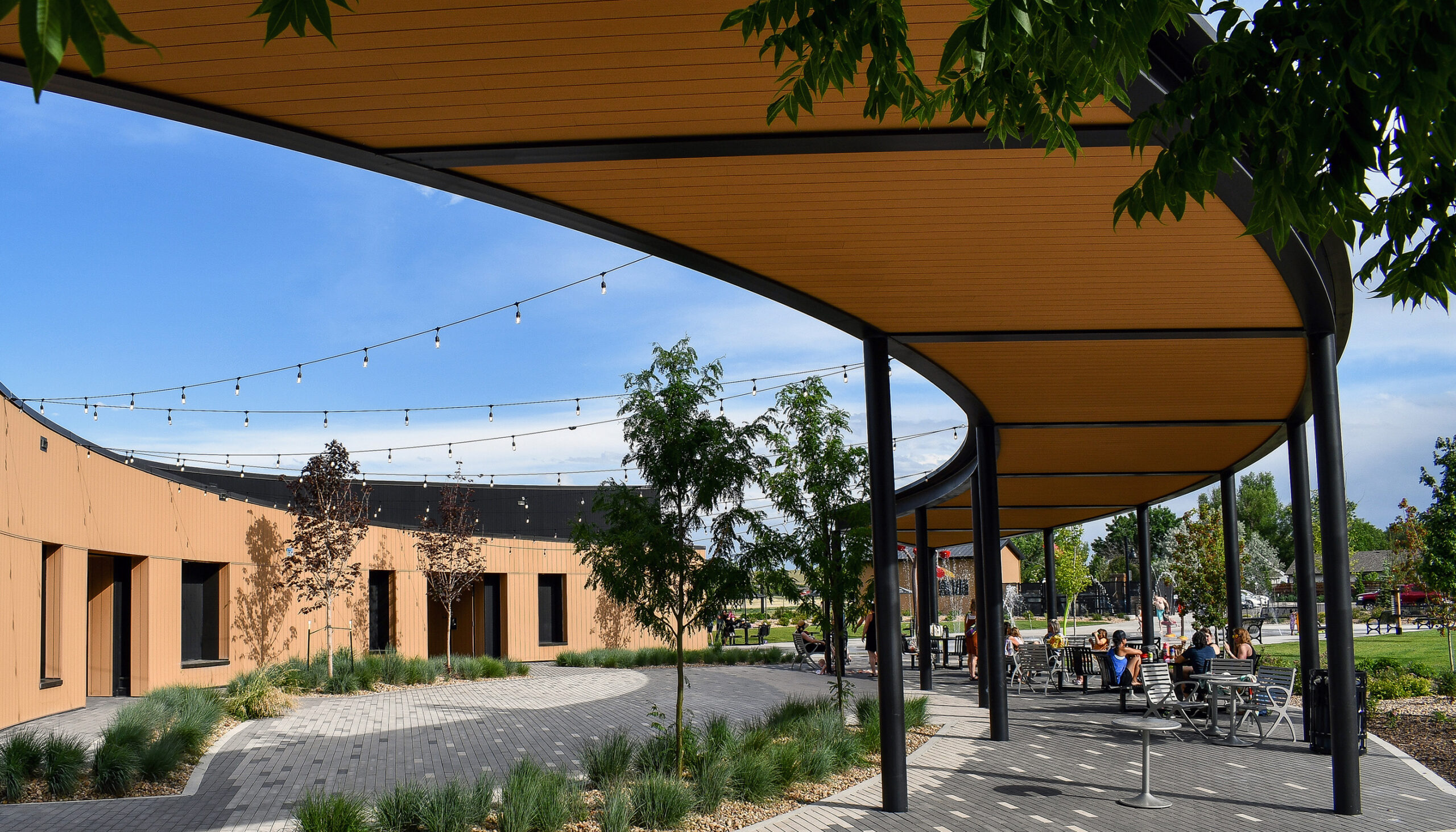 a custom pavilion and concessions building creates an arc canopy over café tables