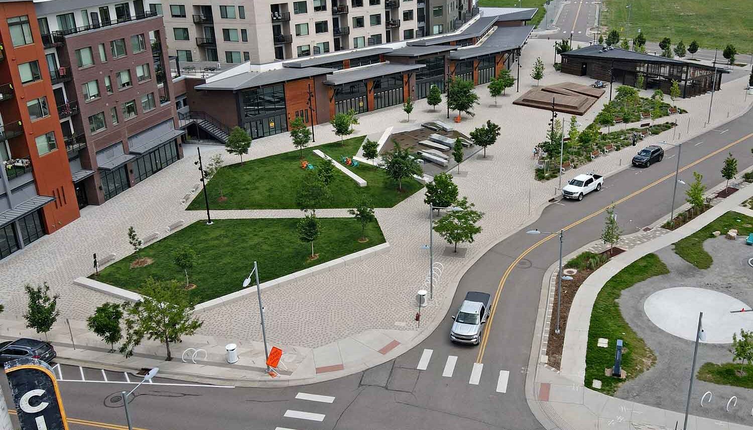 A drone aerial view of the downtown central plaza shows the lawn seating areas, the water feature, stage, and custom pavilion.