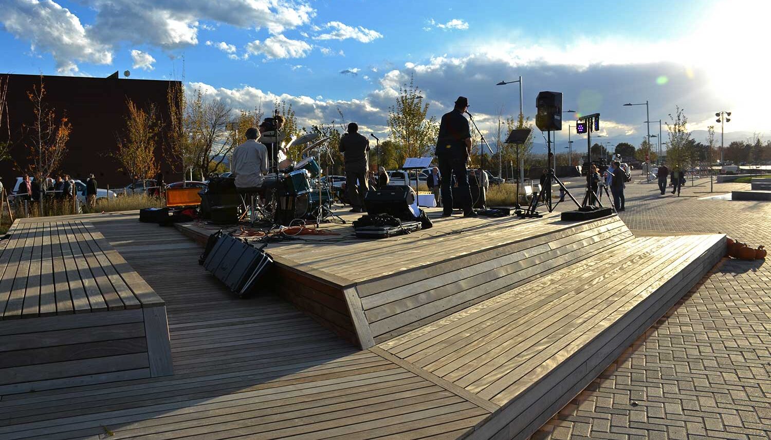 A band plays on a wood platform stage at dusk during the community fall festival.