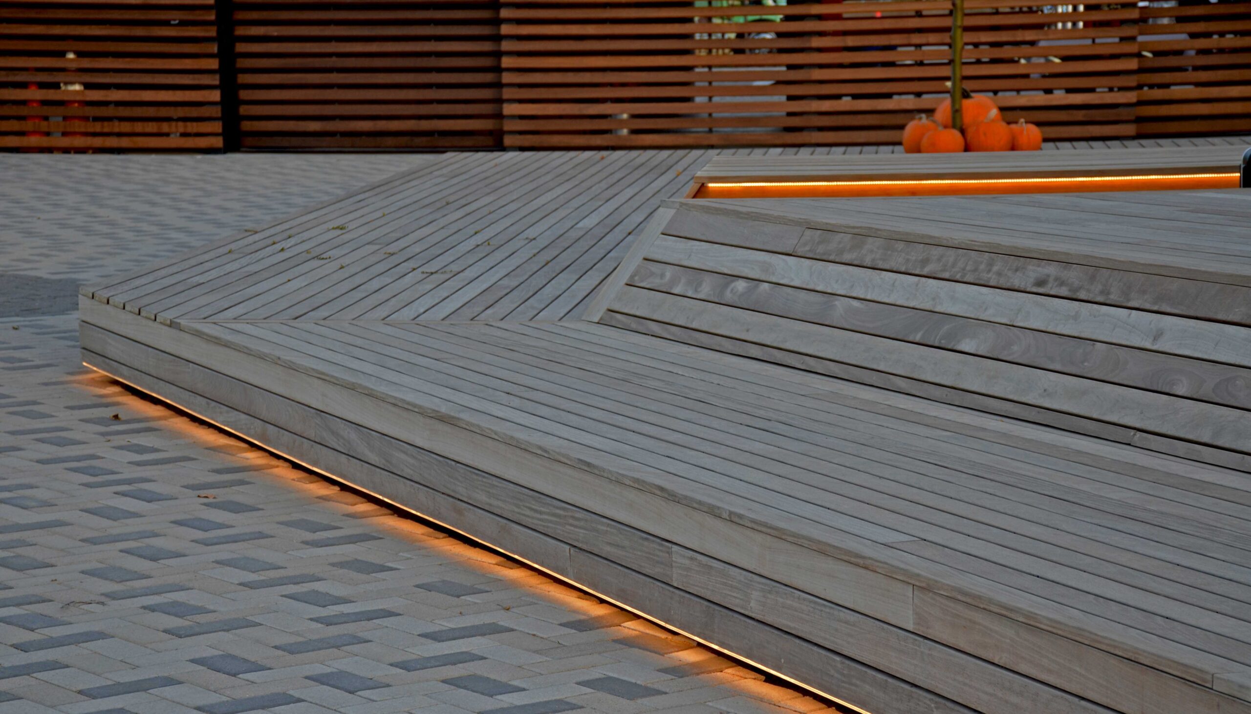 Orange lights follow the linear lines of the base of wood stage at desk.