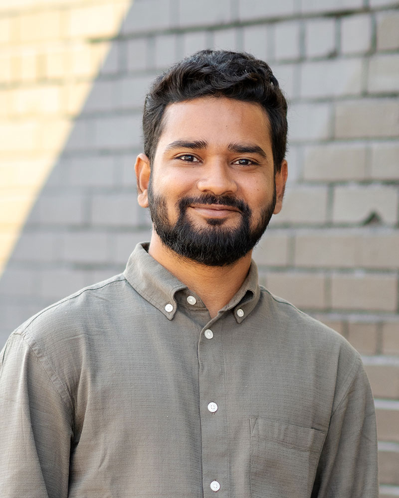 Headshot of Amlan Kumar Dey is standing in front of a painted mural.