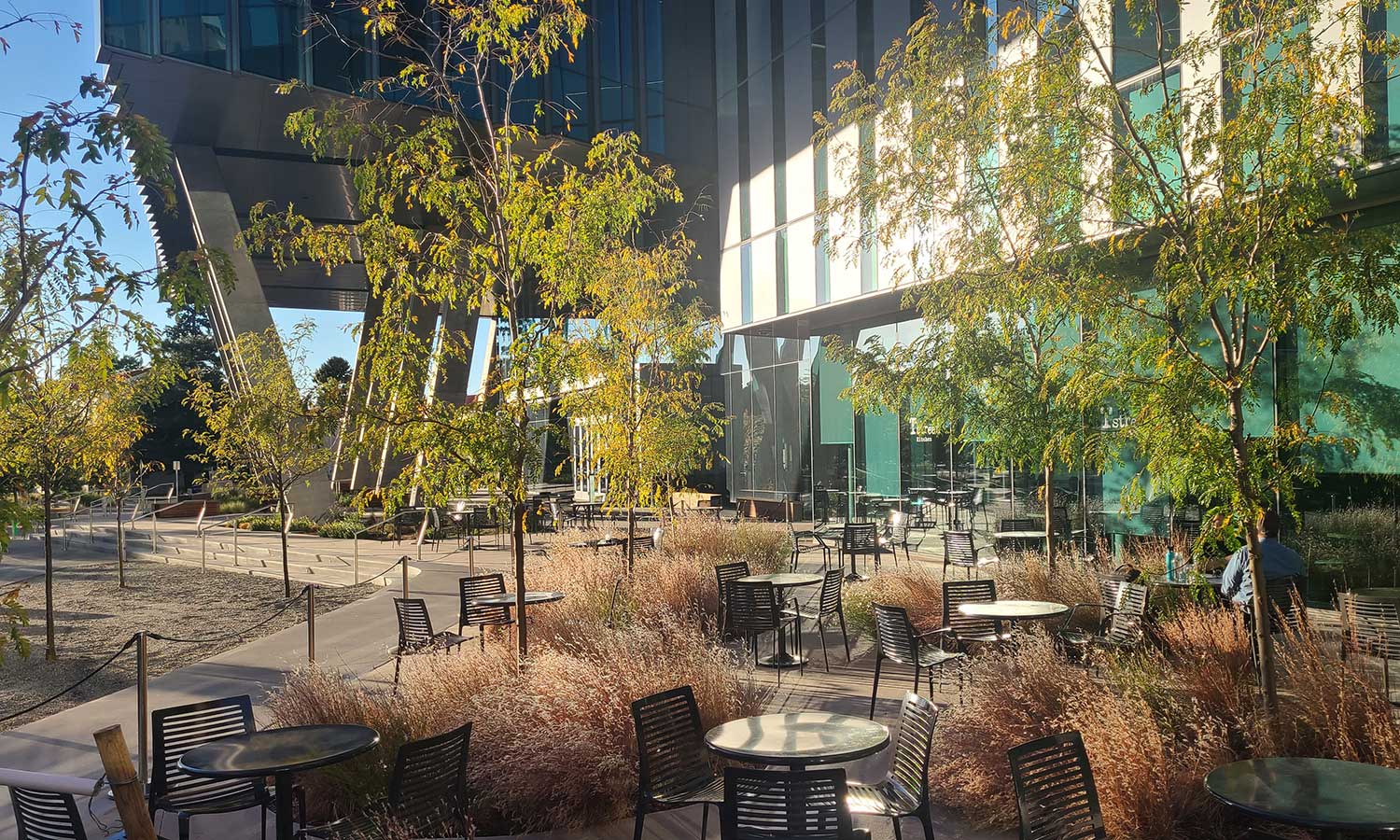A person enjoys the last minutes of sunlight in the outdoor cafe seating area.